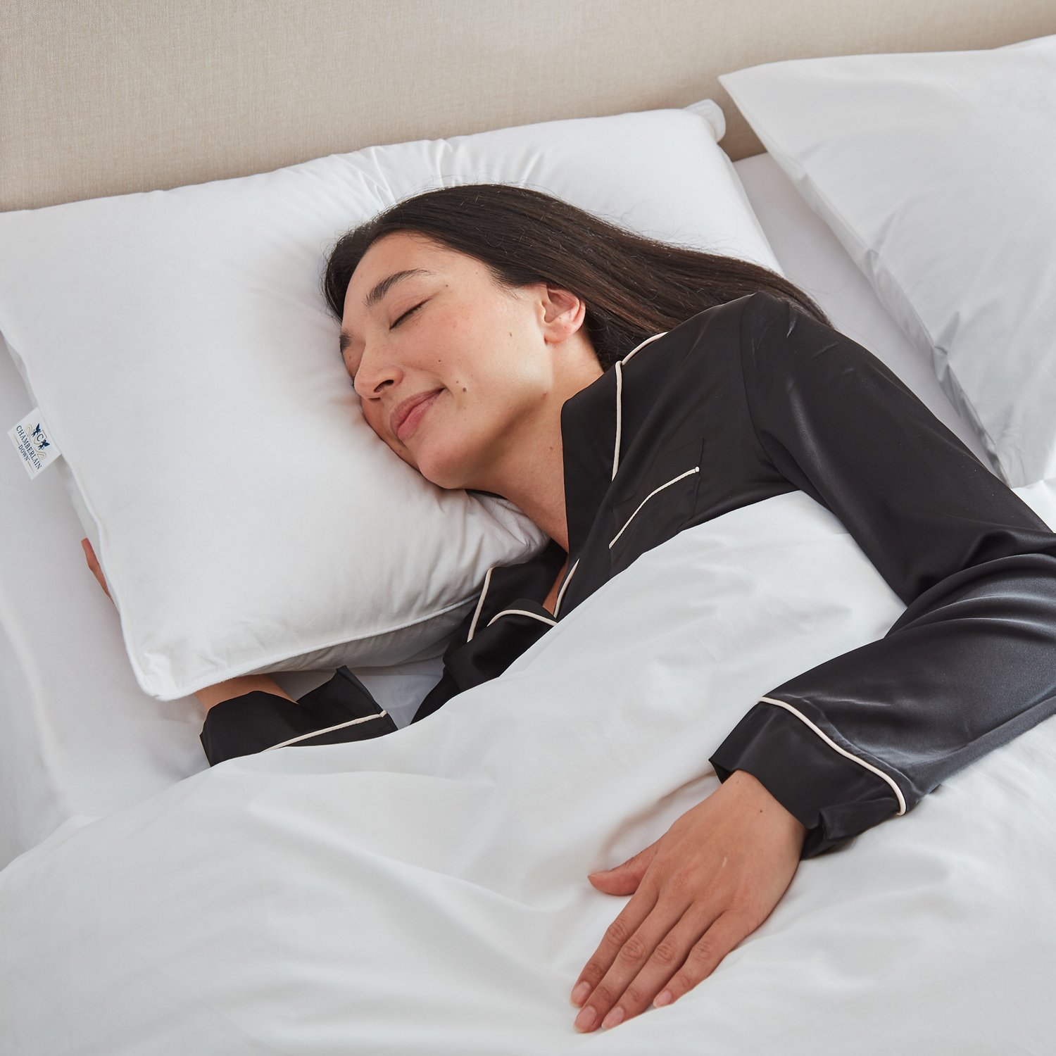 Woman sleeping in bed with Chamberlain Down pillow and comforter